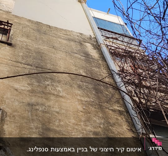 קיר בניין גבוה עם סדקים וצינור מתכת